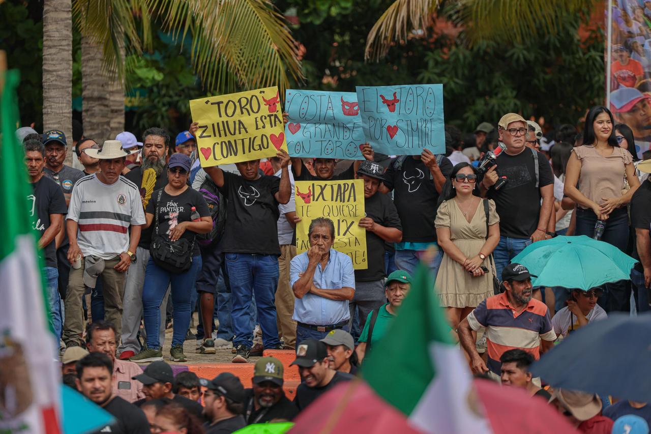 Asistentes con carteles durante la asamblea informativa en Zihuatanejo.